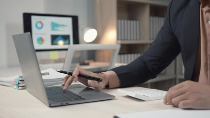Professional businessman analyzing financial data on laptop, using calculator while working at desk in modern corporate office environment - Powered by Adobe