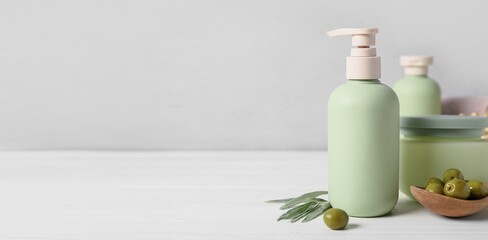 Natural cosmetic products and green olives on light background with space for text