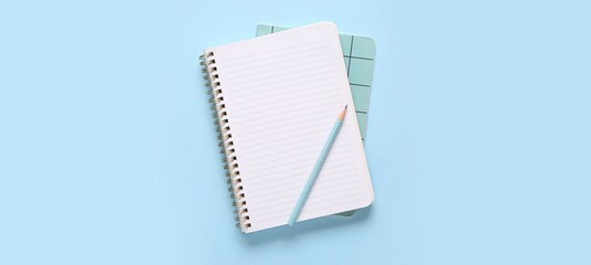 Notebooks and pencil on light blue background