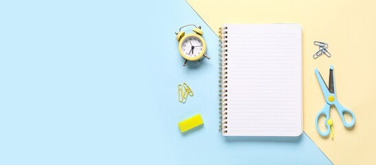 Notebook, alarm clock and stationery on color background with space for text
