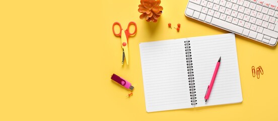 Notebook, PC keyboard and stationery on yellow background with space for text