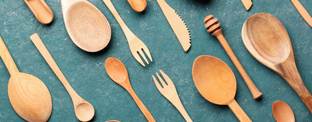 Different wooden kitchen utensils on green background