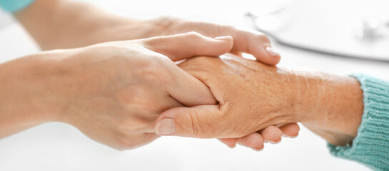 Fototapeta premium Doctor supporting elderly woman in clinic, closeup