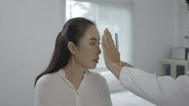 Medical professional measuring precise interpupillary distance using specialized pupillometer during comprehensive eye health examination with young female patient in clinical setting