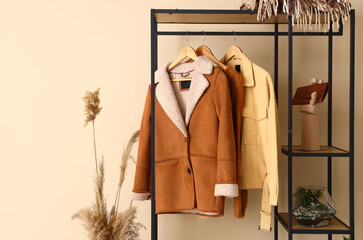 Shelving unit with clothes near beige wall in hall