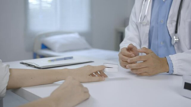 Doctor is using pulse oximeter to measure blood oxygen levels of female patient in hospital room
