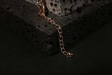 Decorative podium with beautiful chain bracelet on black background