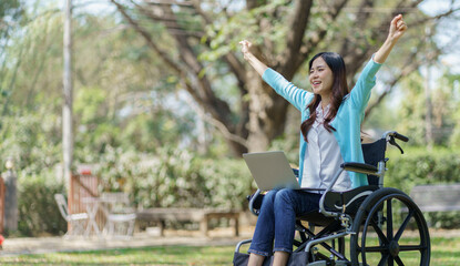 Young asian woman in wheelchair working with laptop