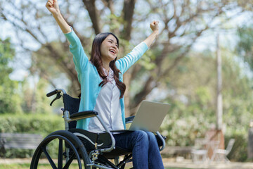 Young asian woman in wheelchair working with laptop