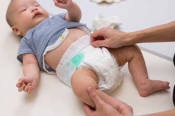 Mother changing baby diaper on table at home