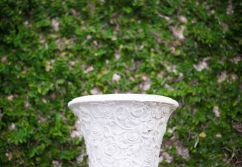 White vase on a background of green plants in the garden.
