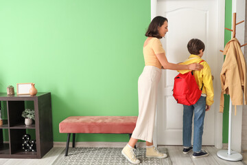 Mother getting her little son ready for school in hallway