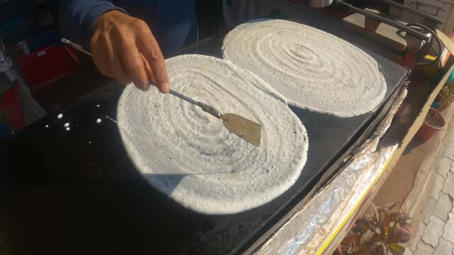 Street Food Vendor Preparing Crispy Dosa on a Hot Griddle at a Bustling Roadside Stall in India