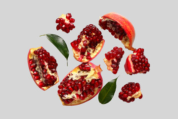 Flying fresh pomegranates and leaves on grey background