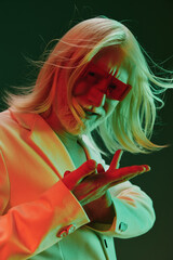 Stylish elderly man with long white hair in red sunglasses striking a pose, illuminated by green...