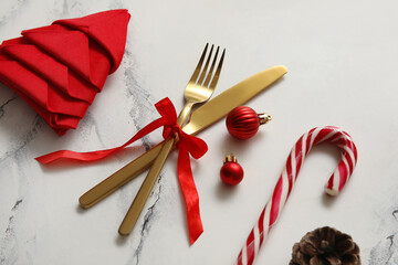 Festive table setting with golden cutlery and Christmas decorations on white marble background