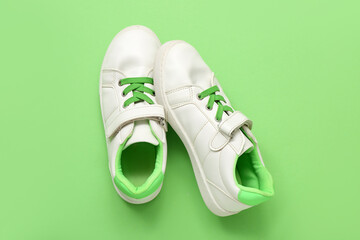 Pair of stylish child's sneakers on green background
