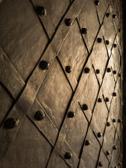 Old metallic door with decorative iron studs and diagonal pattern, close-up.