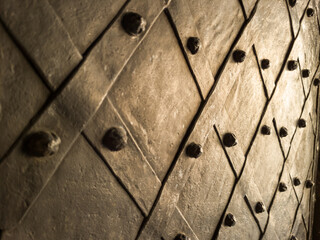 Old metallic door with decorative iron studs and diagonal pattern, close-up.