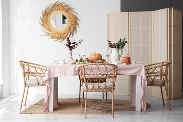 Autumn table setting decorated for Thanksgiving Day with pumpkins and eucalyptus branches in light dining room