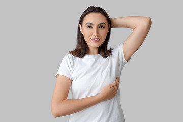 Young woman checking her breast on light background. Cancer awareness concept