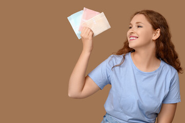 Beautiful young woman with menstrual pads on brown background