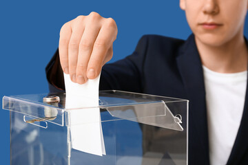 Voting young man near ballot box on blue background, closeup