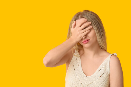 Young woman doing facepalm on yellow background