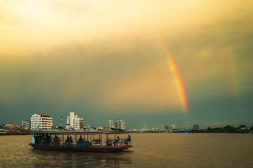 Image of a boat ferrying people to the other side after a rain and a rainbow formed. Concept of...