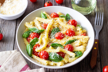 Pasta casarecce with tomatoes, basil and cheese. Italian cuisine. Vegetarian food.
