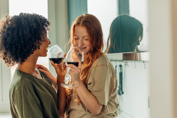 Lesbian couple drinking wine and enjoying intimate moments in kitchen