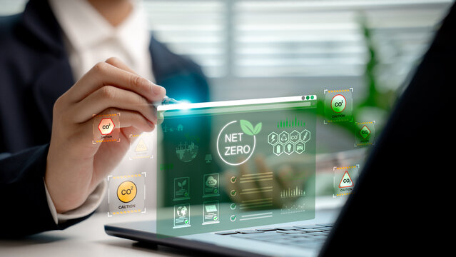 Businessperson analyzing net zero carbon dashboard hologram, showing CO2 emission data and sustainable energy icons, highlighting carbon reduction and environmental responsibility concept.