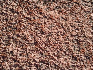 Rough wall surface covered with decorative plaster and putty. Painted pink. Background bumpy texture. Decorative materials.