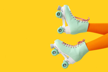 Legs of woman in roller skates on yellow background