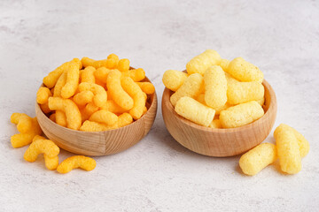 Wooden bowls with different tasty salty corn sticks on light background