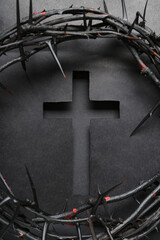 Cut black paper in shape of cross with crown of thorns on dark background. Good Friday concept
