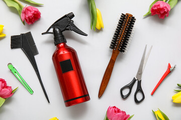Hairdresser's tools with beautiful tulips on grey background