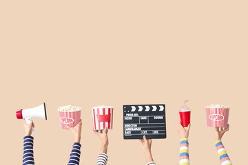 Many hands with movie clapper, buckets of popcorn and megaphone on beige background