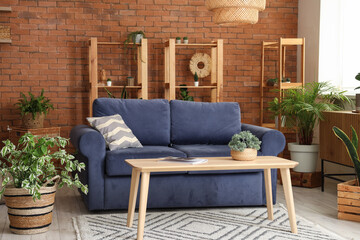 Interior of loft style living room with sofa, shelving units, table and houseplants