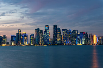 Obraz premium Panoramic view of the tall skyscrapers of Doha in Qatar At sunset. Persian Gulf countries. Doha skyline view with sea