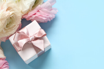 Beautiful ranunculus flowers with gift box on blue background