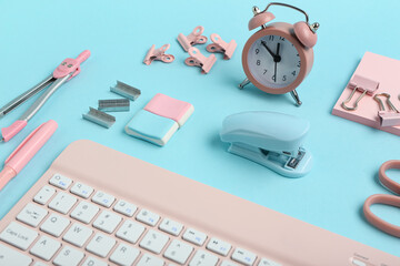 Composition with keyboard, alarm clock and stationery on blue background