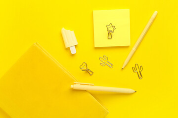 Stylish notebook with pens, sticky notes and marker on yellow background