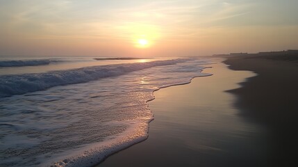 Serene sunrise paints the ocean waves with golden hues as they gently caress the sandy shore