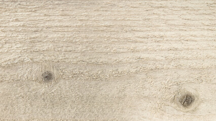 Light-colored wooden surface with natural grain patterns and knots, showcasing the texture and...