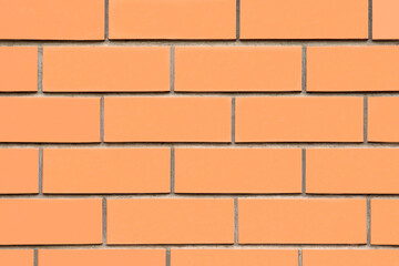 Textured orange brick wall with evenly spaced bricks, showcasing a clean and modern design, ideal for backgrounds or architectural projects with copy space