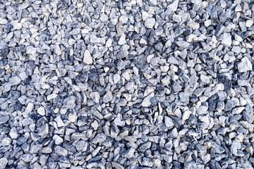 Close-up view of a textured surface covered in small gray stones and gravel, showcasing the natural...