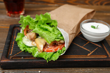 Tasty doner kebab and sauce on wooden background, closeup