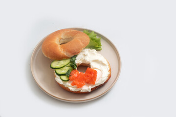 Burger with red fish, cucumber and cream cheese on a plate on a white background