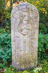 Old Runestone with runes and a cross in nature
